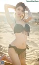 A woman in a bikini posing on a beach.