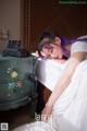 A woman with purple hair laying on a bed next to a dresser.