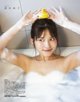 A woman in a bathtub with a rubber duck on her head.