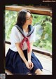 A woman in a sailor outfit sitting on a window sill.