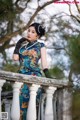 A woman in a blue dress and black gloves standing on a railing.