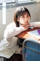 A young woman sitting at a desk in a classroom.