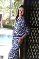 A woman leaning against a wall next to a pool.