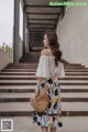 A woman wearing a white off the shoulder top and a floral skirt.