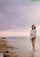 A woman standing in the water on a beach.