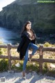 A woman leaning on a wooden fence by the ocean.