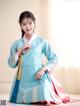 A woman in a blue and pink hanbok is posing for a picture.