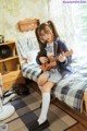 A girl sitting on a bed playing a ukulele.