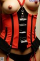 A woman wearing a red and black corset with a black belt.